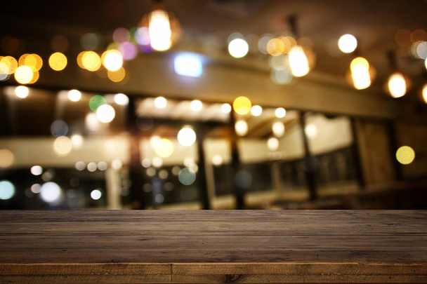 wooden table in front of abstract restaurant lights background - Photo, image