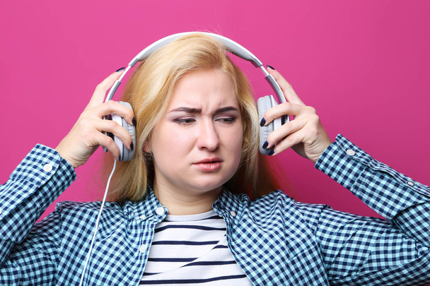 Young woman listening music with headphones on pink background - Foto, imagen
