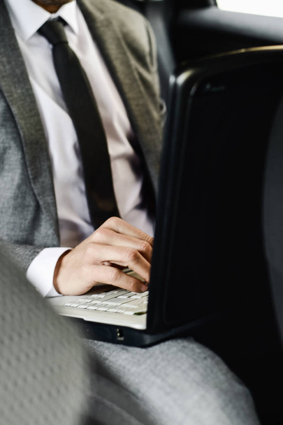 Empresário usando um laptop em um carro
 - Foto, Imagem