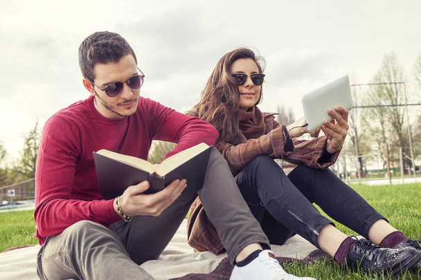 nice couple boyfriends relaxing on meadow looking at book and sm - 写真・画像