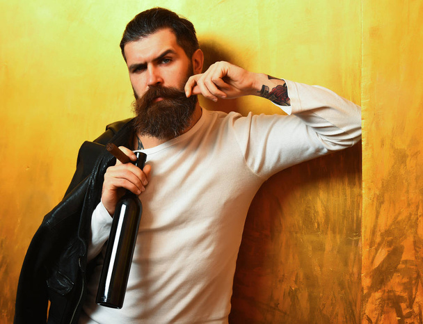 Bearded brutal caucasian hipster holding bottle and smoking cigar - Foto, imagen