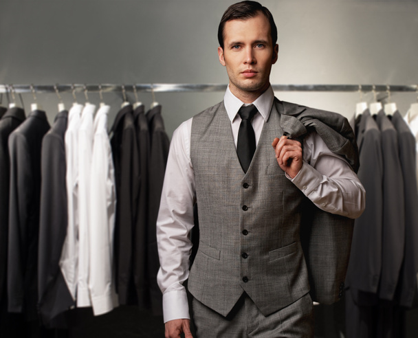 Homme d'affaires en gilet classique contre rangée de costumes dans le magasin
 - Photo, image