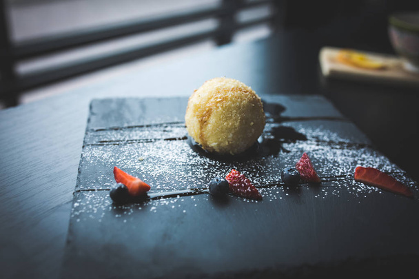 Grilled ice-cream in coconut with sauce on black stone plate. Asian food background. Eating concept. Restaraunt place with wooden table. Copy space for text, design. - 写真・画像
