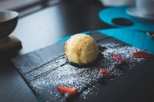 Grilled ice-cream in coconut with sauce on black stone plate. Asian food background. Eating concept. Restaraunt place with wooden table. Copy space for text, design. - Photo, Image