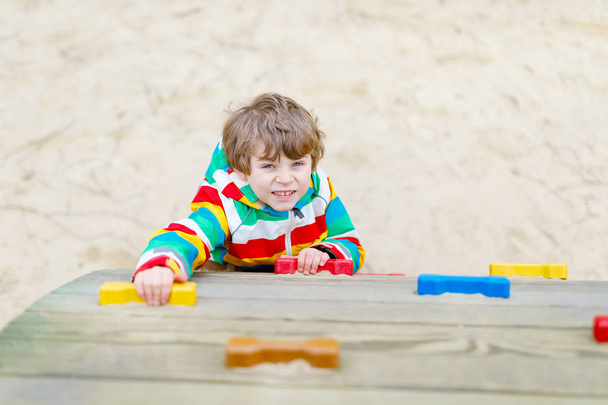Niño rubio feliz divirtiéndose y escalando en el patio al aire libre
 - Foto, Imagen