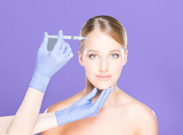 Dokter maken van injectie in gezicht van vrouw - Foto, afbeelding