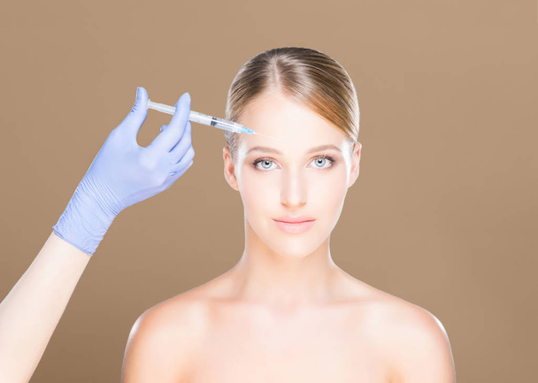 Doctor making injection into face of woman - Foto, afbeelding