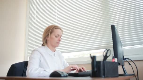 Atractiva mujer de negocios que trabaja con una computadora y documentos en la oficina
 - Imágenes, Vídeo