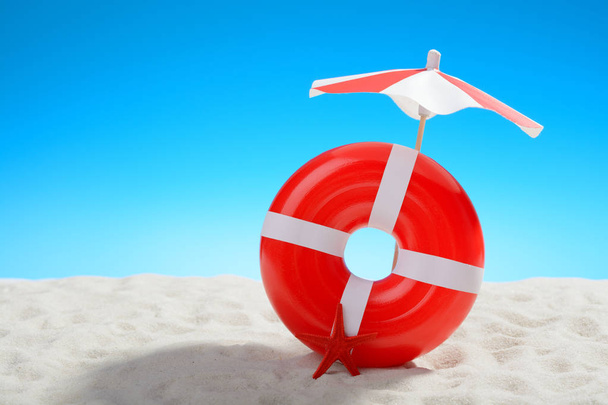 Parapluie et anneau de natation à la plage
 - Photo, image