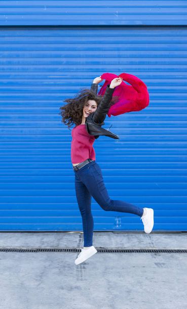 Young woman jumping and  having fun with a red scarf over blue b - Foto, Bild