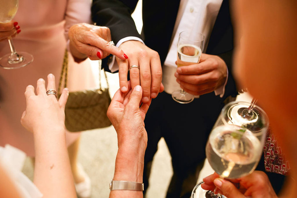 Old ladies look at newlyweds rings holding their hands  - Zdjęcie, obraz