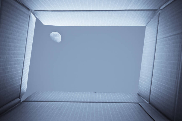 段ボール箱の中からの眺め。段ボール箱の外の空に満月 - 写真・画像