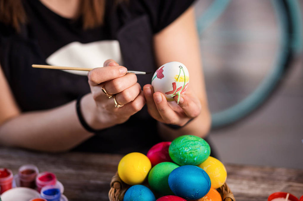 colouring eggs for eastertime at home.Happy easter! A mother,girl painting Easter eggs. Happy family preparing for Easter.decorating Easter eggs, woman hands hold a paintbrush and paint - Photo, Image