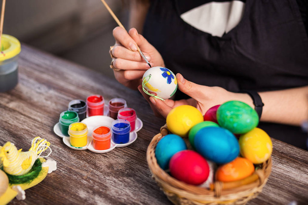 colorear los huevos para la Pascua en casa. ¡Feliz Pascua! Una madre, una niña pintando huevos de Pascua. Familia feliz preparándose para los huevos de Pascua Easter.decorating, las manos de la mujer sostienen un pincel y pintura
 - Foto, Imagen