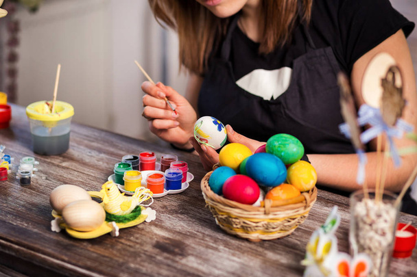 colouring eggs for eastertime at home.Happy easter! A mother,girl painting Easter eggs. Happy family preparing for Easter.decorating Easter eggs, woman hands hold a paintbrush and paint - Foto, Imagem