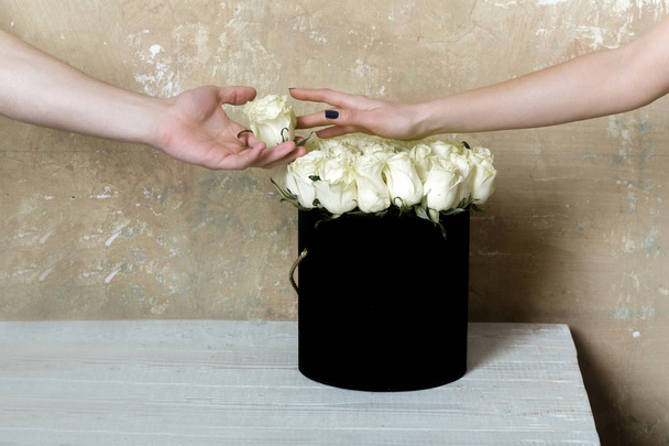 Romantic date with flowers. Bouquet of white roses and two hands of happy couple. Flowers for a girl from a beloved man - Photo, image