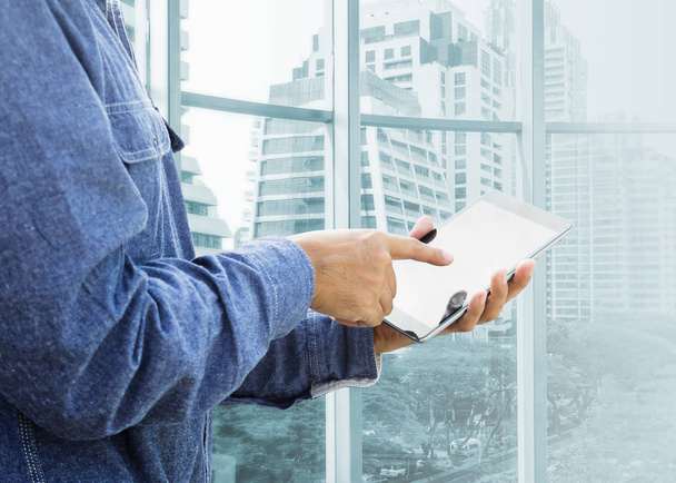 Businessman using digital tablet with modern building  - Photo, Image