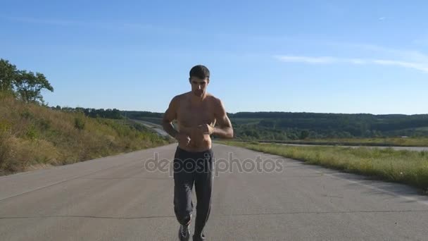 Sprint coureur homme jogging à l'autoroute. Athlète sportif masculin s'entraînant en plein air en été. Jeune homme fort musclé faisant de l'exercice sur la route rurale pendant l'entraînement. Style de vie sain actif à l'extérieur. Gros plan
 - Séquence, vidéo
