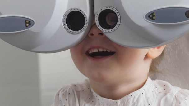 Szemészeti Klinika - imádnivaló szőke kislány ellenőrzi a vision látás, közelről - Fotó, kép