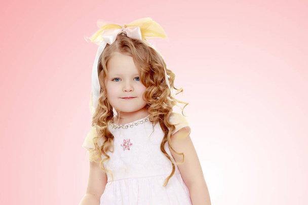 Beautiful curly-haired little girl with a bow on her head. - Φωτογραφία, εικόνα