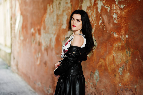 Young goth girl on black leather skirt and jacket against grunge - 写真・画像