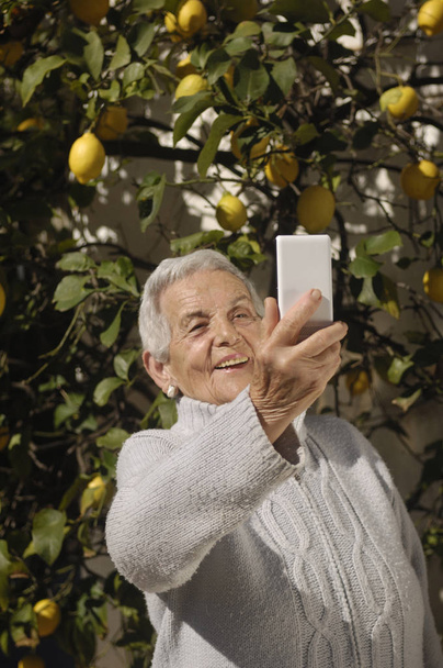 Vecchia donna che fa un selfi all'esterno
 - Foto, immagini