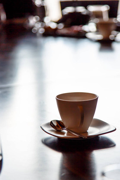 Crema (beige) Taza para café de pie sobre una mesa negra en la ba
 - Foto, imagen