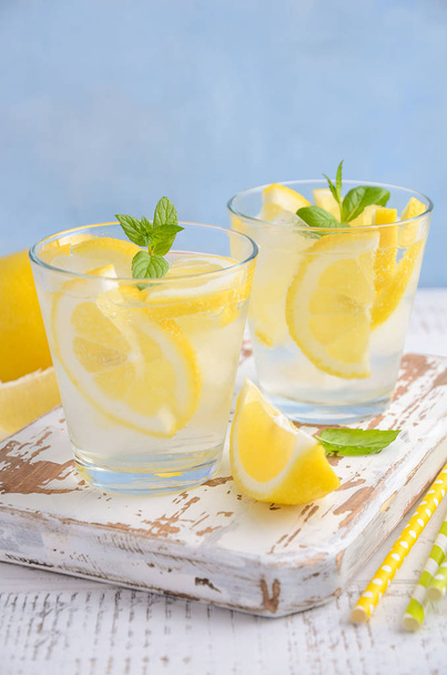 kaltes erfrischendes Sommergetränk mit Zitrone und Minze auf Holzgrund. - Foto, Bild