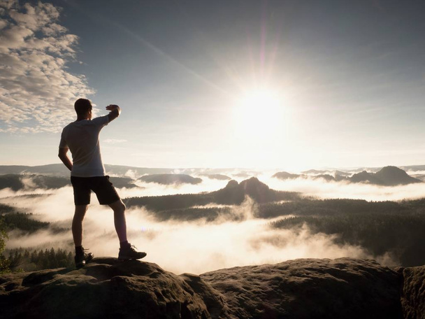 Mann auf dem Gipfel eines Berges mit Blick auf die neblige Landschaft. fühlen Sie sich frei - Foto, Bild