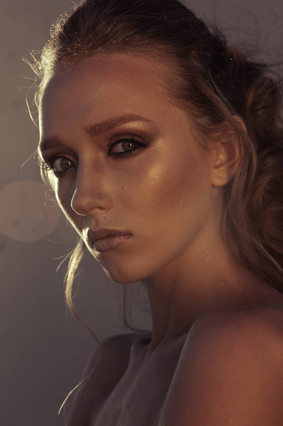 Glamour portrait of young fashion woman face with bright evening golden make up for party. Warm toning - Foto, Imagem