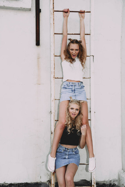 стиль життя і концепція людей: Модний портрет двох стильних дівчат найкращих друзів у джинсових спідницях, на відкритому повітрі на даху. Щасливий літній час для розваги
. - Фото, зображення