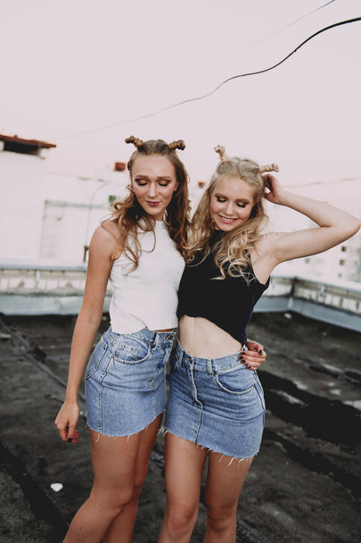 style de vie et concept de personnes : Portrait de mode de deux filles élégantes meilleurs amis portant des jupes en jeans, à l'extérieur sur le toit. Bonne heure d'été pour s'amuser
. - Photo, image