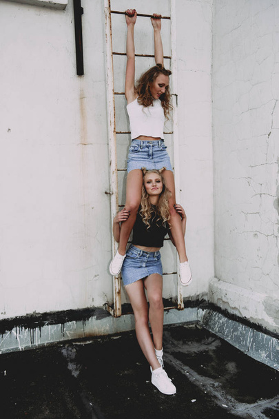 koncepcja życia i ludzi: moda portret dwa stylowe dziewczyny przyjaciele nosi spódnice jeans, na zewnątrz na dachu. Szczęśliwy czas letni dla zabawy. - Zdjęcie, obraz