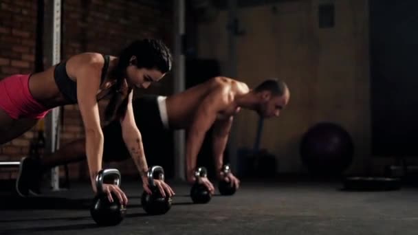 Couple doing push ups with kettlebells - Footage, Video