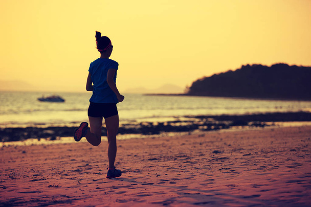 Young woman running at sandy beach - 写真・画像