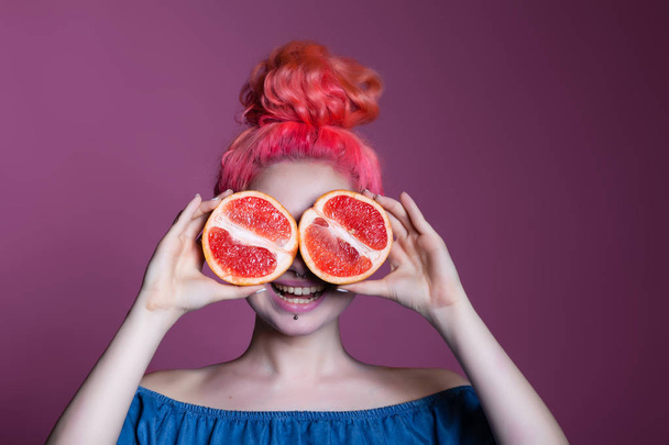 girl with pink hair with Grapefruit halves on lilac background, place for text - Zdjęcie, obraz