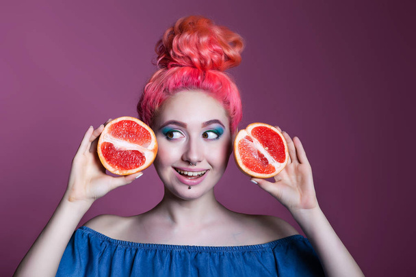 girl with pink hair with Grapefruit halves on lilac background, place for text - Foto, immagini