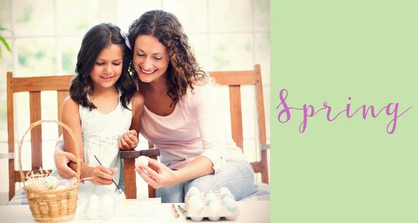 Composite image of happy mother and daughter painting easter eggs  - Valokuva, kuva
