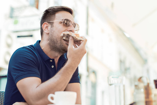 Hombre comiendo una rebanada de pizza
  - Foto, Imagen