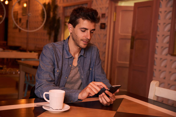 Hombre joven escribiendo mensaje en el teléfono inteligente
 - Foto, imagen