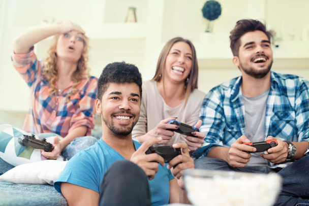Friends having fun on the couch with video games - Фото, изображение