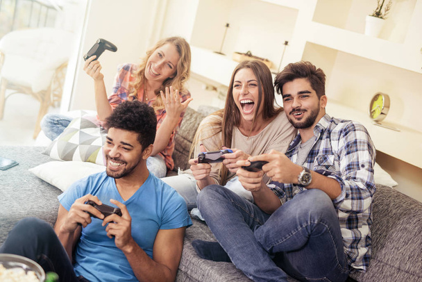 Friends having fun on the couch with video games - Foto, afbeelding