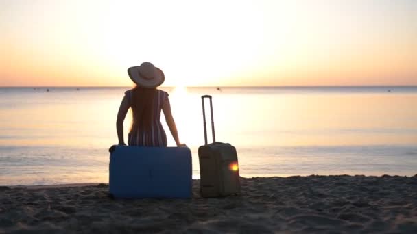 Nuori nainen istuu matkalaukussa lähellä merta.
 - Materiaali, video