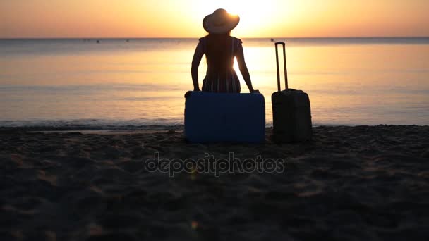 Młoda kobieta siedzi na walizkę w pobliżu morza - Materiał filmowy, wideo
