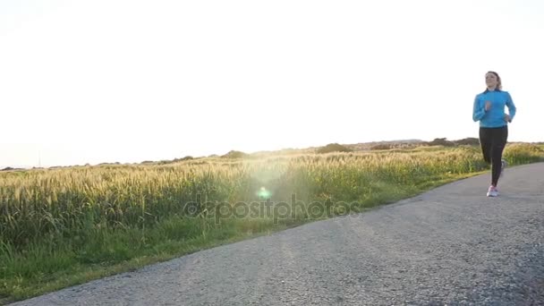 Νεαρή γυναίκα δρομέας τρέχει στο δρόμο Ανατολή του ηλίου. Γυμναστήριο έννοια - Πλάνα, βίντεο