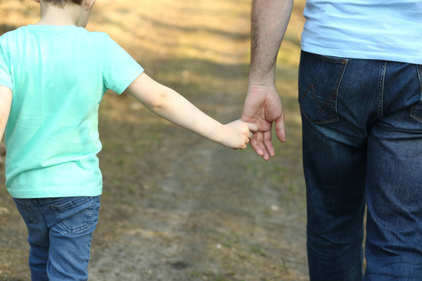 Родитель держит за руку своего сына
 - Фото, изображение