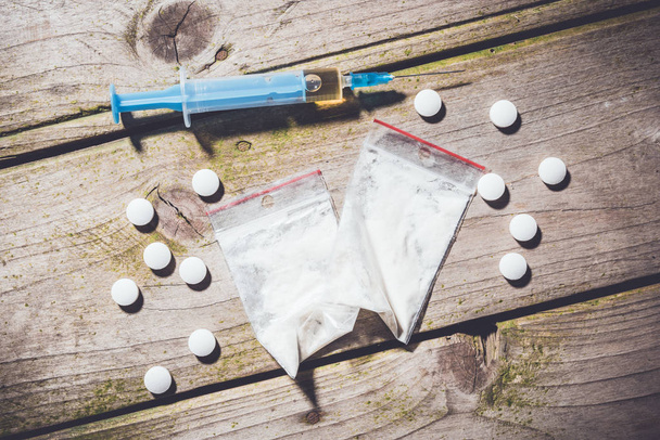 Overhead shot of hard drugs and alcohol on wooden table. - Foto, afbeelding