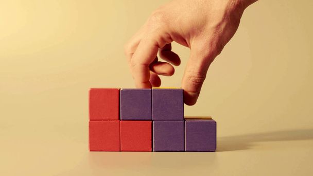 Чоловік рука збирає кольорові кубики
 - Фото, зображення