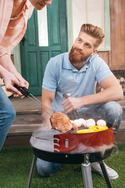 couple grilling meat and vegetables - Photo, Image