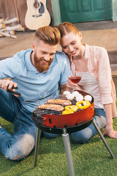 couple grilling meat and vegetables - Фото, изображение
